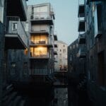 Buildings with lit windows reflect in dark water.