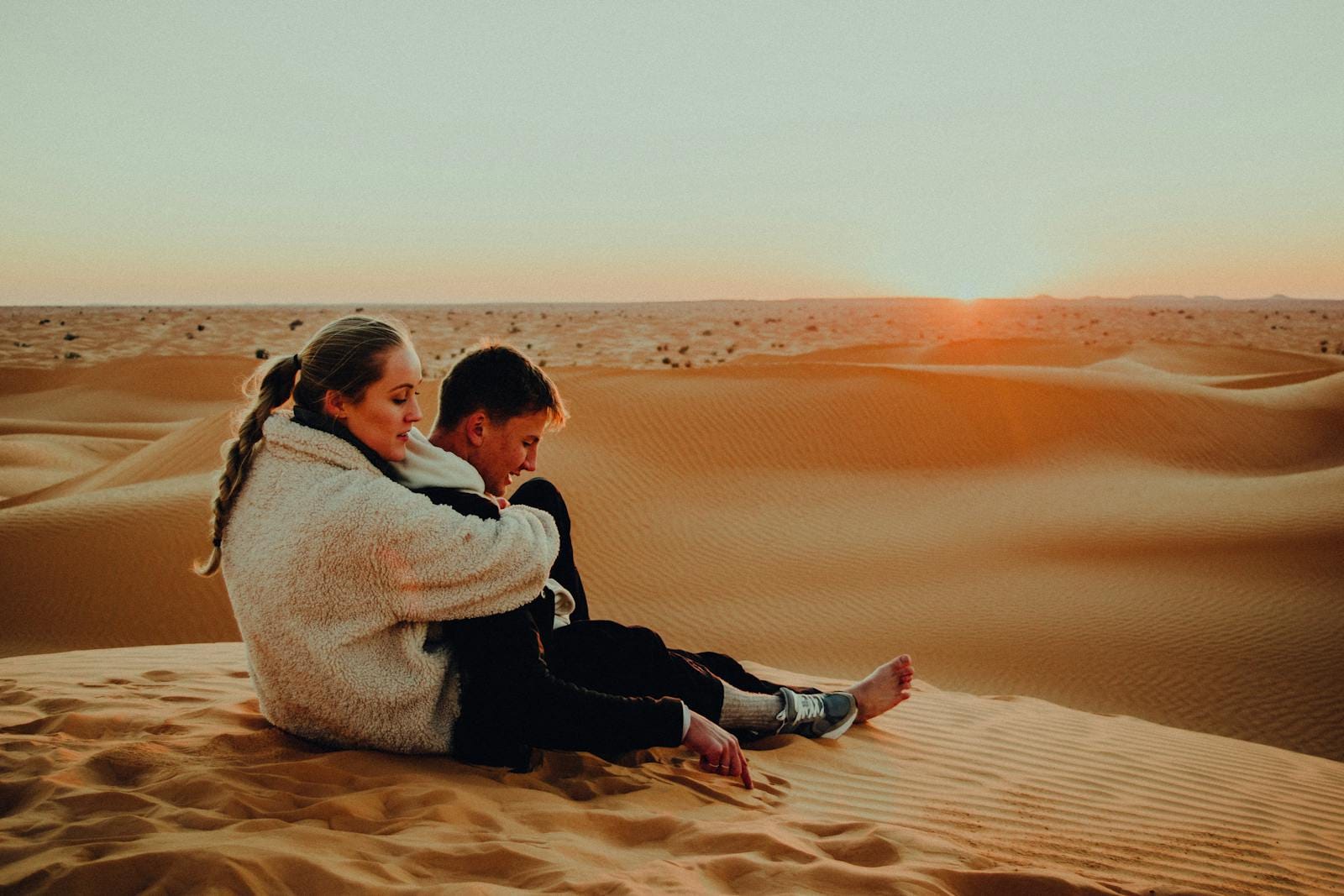 A couple enjoys a serene sunset in the vast sand dunes of morocco, creating a moment of tranquility and connection.Morocco weather December,morocco in december