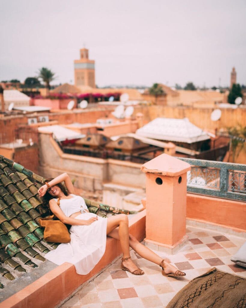 Woman relaxing on a rooftop in Marrakesh, Morocco, capturing the vibrant urban skyline and warm tones of the city.Photo Spots in Marrakech