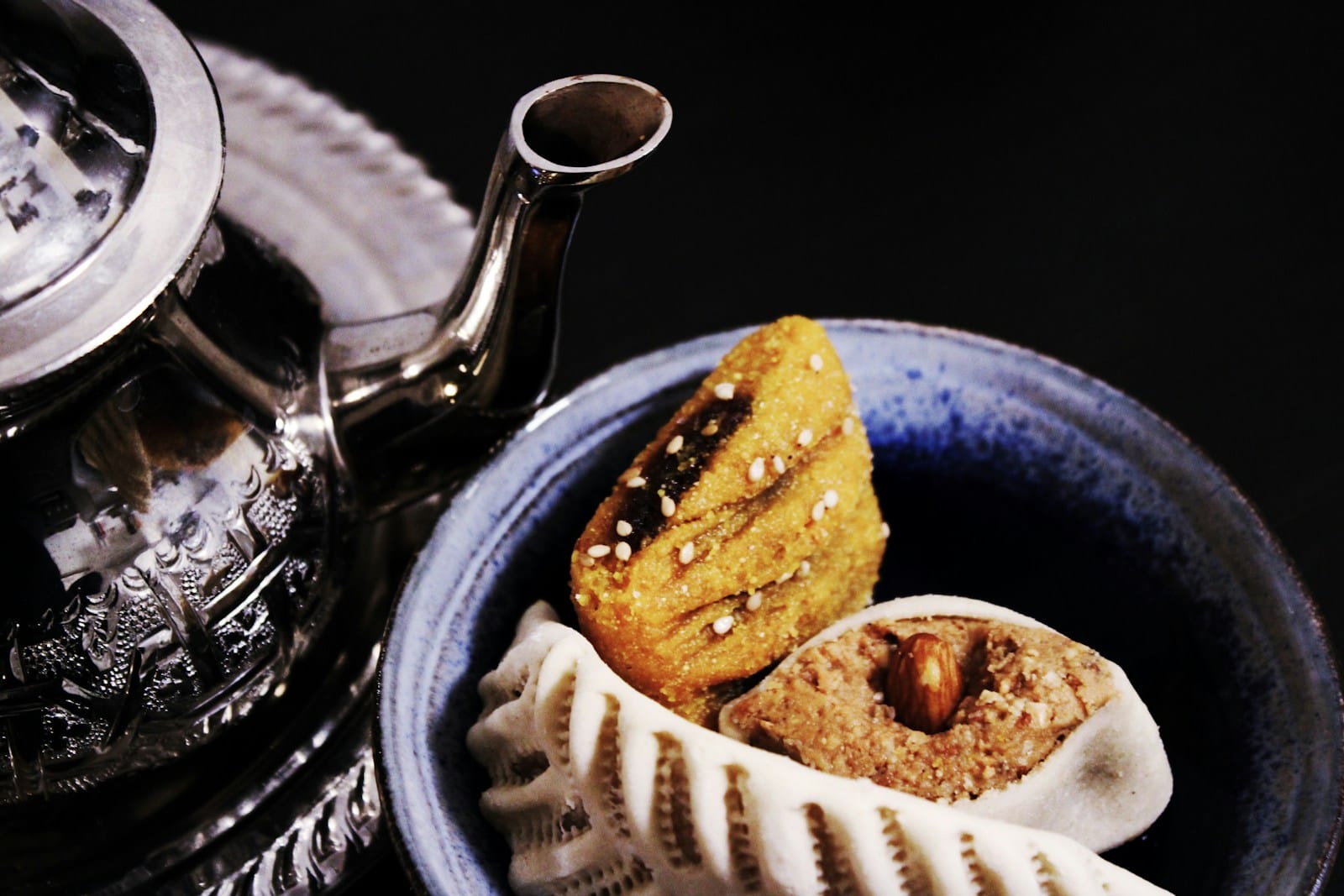moroccan pastries on bowl beside teapot