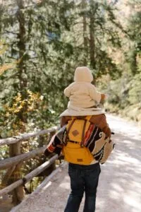 Father carrying child on shoulders through a scenic fall forest trail, enjoying nature's beauty.10 day Morocco family vacation itinerary
