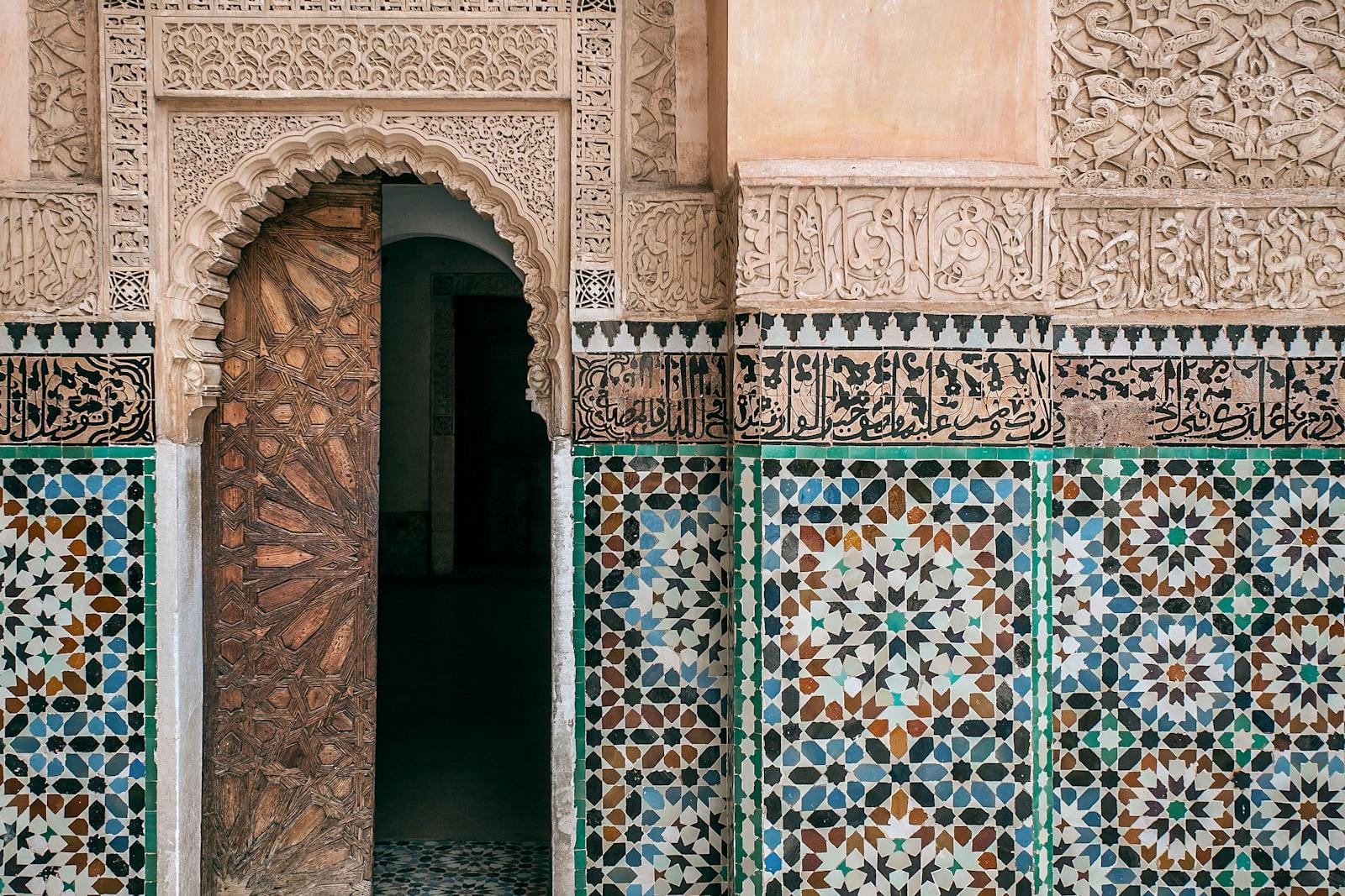 Aged house exterior with arched entrance door and geometric decor on stone walls in city in daylight.Moroccan Tiles Zellige