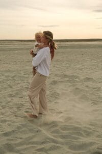 A mother and baby walking on a sandy beach during sunset, sharing a joyful moment.10 day Morocco family vacation itinerary