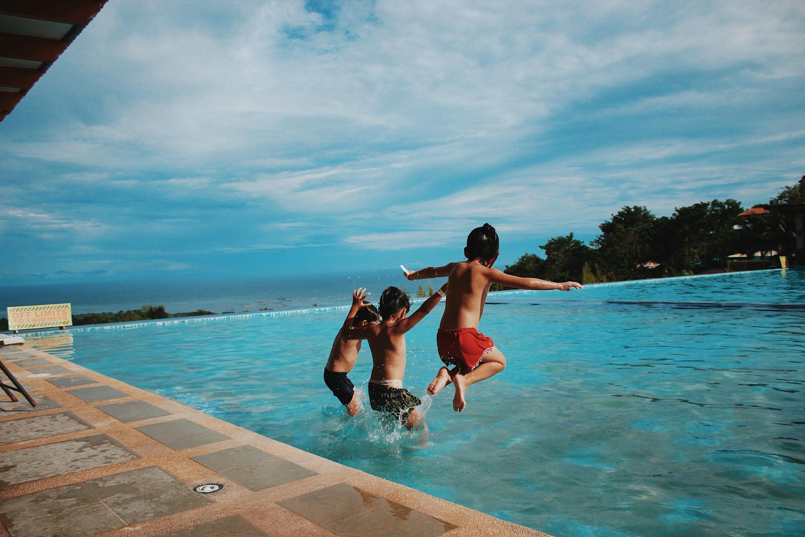 Two children joyfully jump into a pool on a sunny day, embodying excitement and summer vibes.10 day morocco family friendly vacation itinerary
