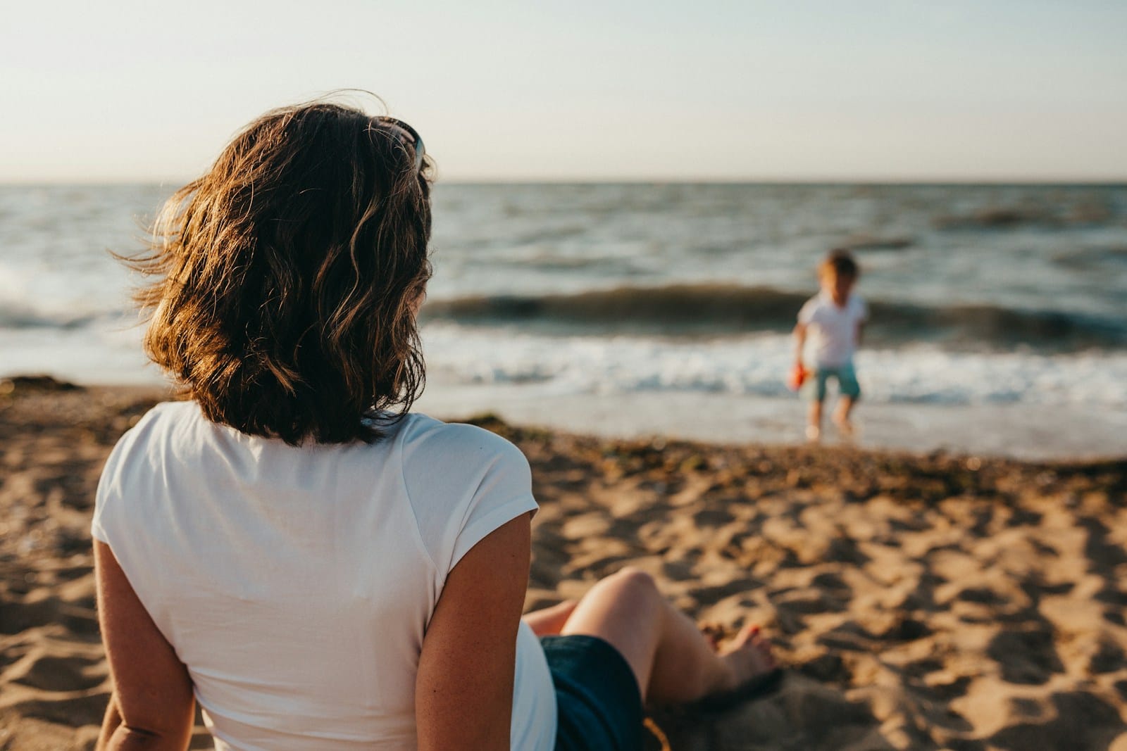 woman watching child playing on beach during daytime,family Morocco tour packages