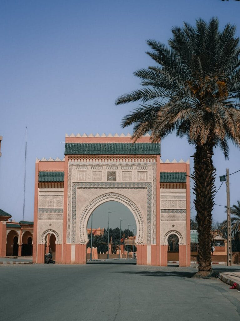 Beautiful Moroccan archway in Rissani with palm trees under a clear blue sky.,Rissani Morocco