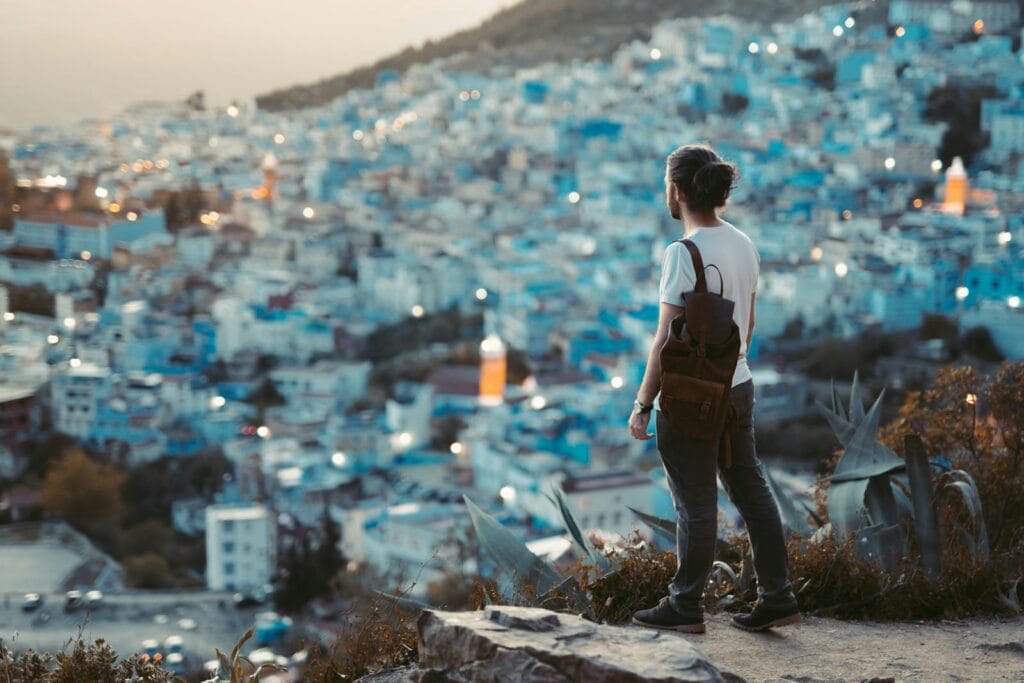 Traveler overlooks the blue city of Chefchaouen at dusk, capturing the vibrant essence of this Moroccan gem.Weather In Morocco in June
