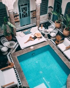 Elegant indoor pool with a woman lounging, set within a Moroccan riad in Marrakesh.moroccan riad