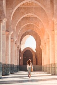 A woman walks through the stunning arches of Hassan II Mosque, Casablanca, highlighting Islamic architecture.Hassan II Mosque