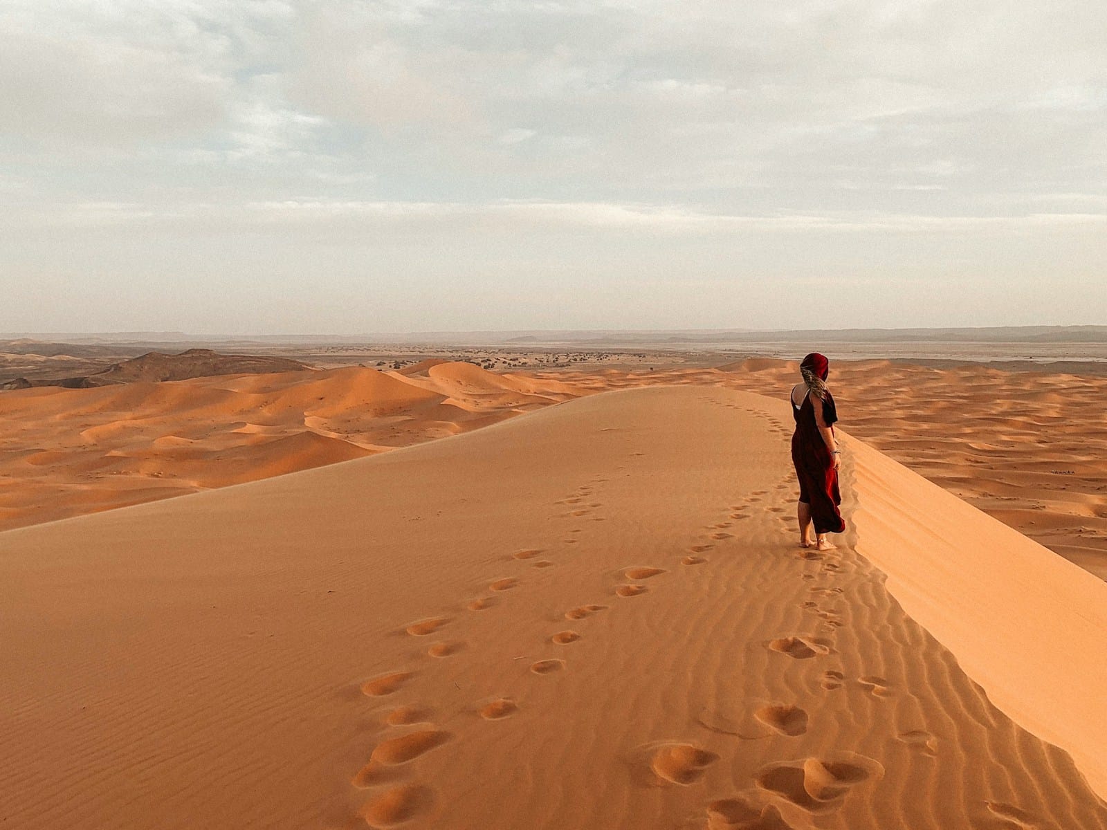 women in black jacket walking on desert during daytime,Merzouga Weather in December