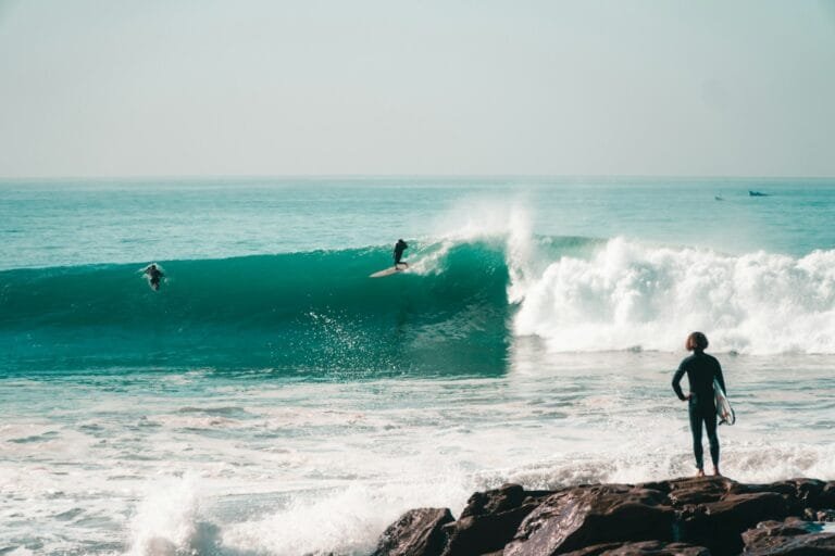 a person standing on a rock in front of a wave.weather in taghazout in december