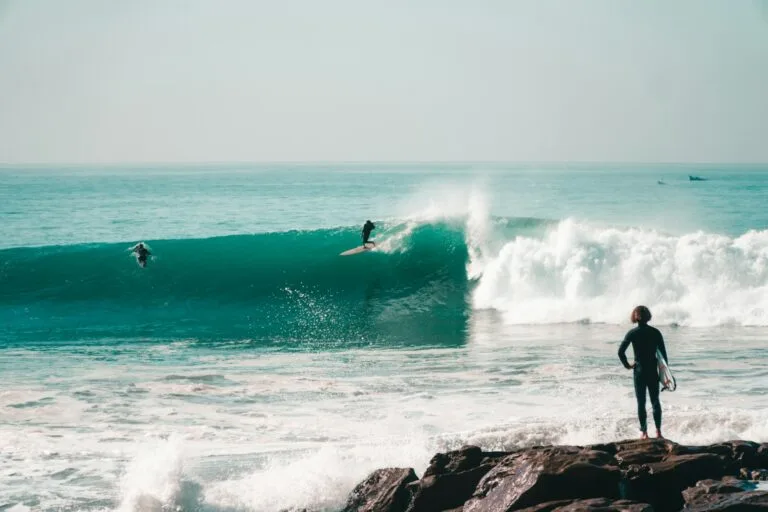 a person standing on a rock in front of a wave.weather in taghazout in december