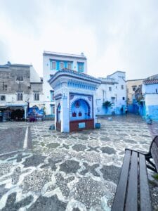 a bench sitting in front of a blue building.chefchaouen