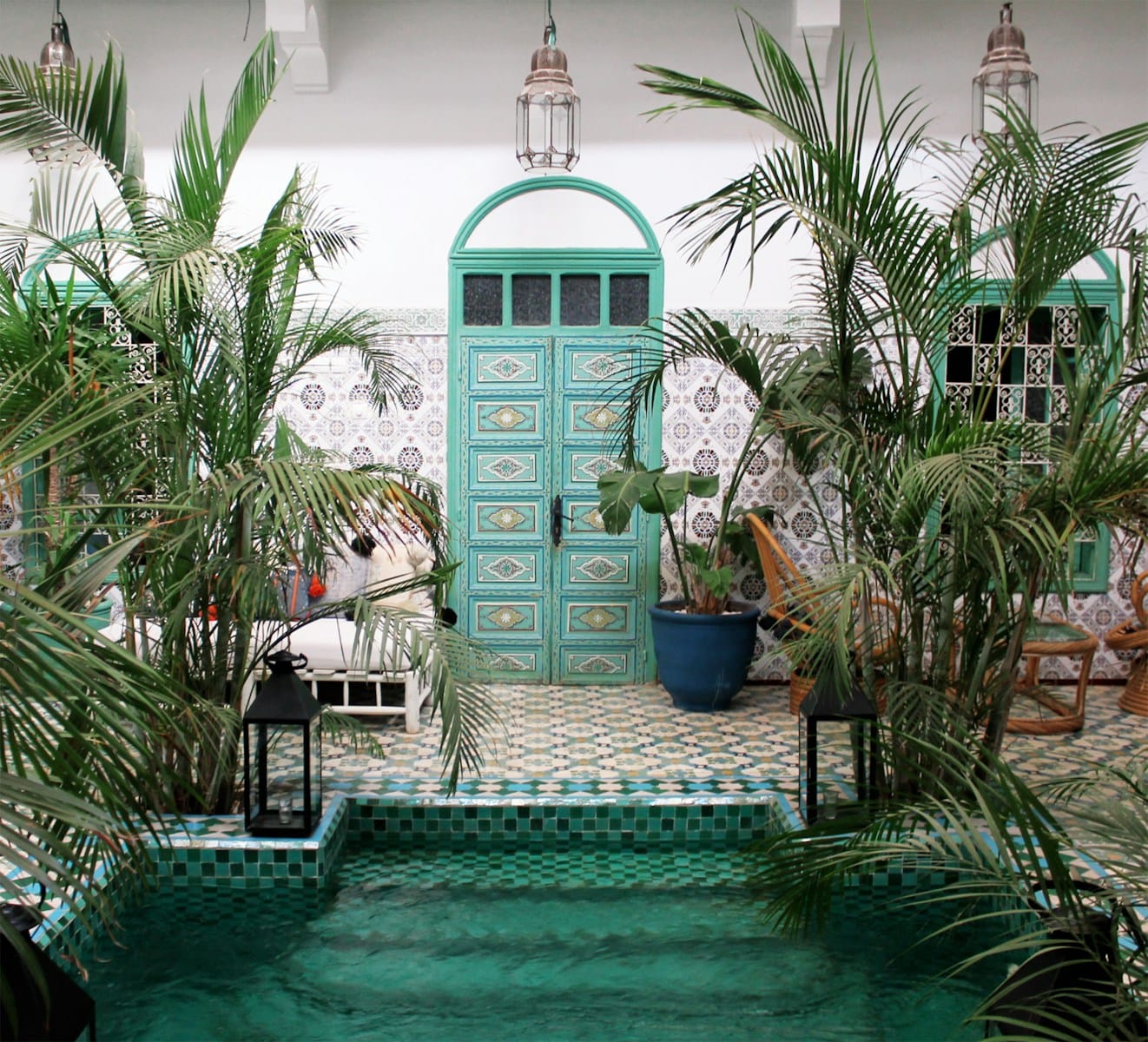 a pool with a green door surrounded by palm trees,Weather in April Morocco