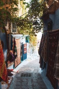Picturesque narrow alley with vibrant rugs in the blue city of Chefchaouen, Morocco..Holiday in Morocco During Ramadan
