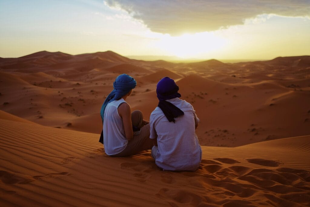 two men sitting on sand dunes.Merzouga Morocco