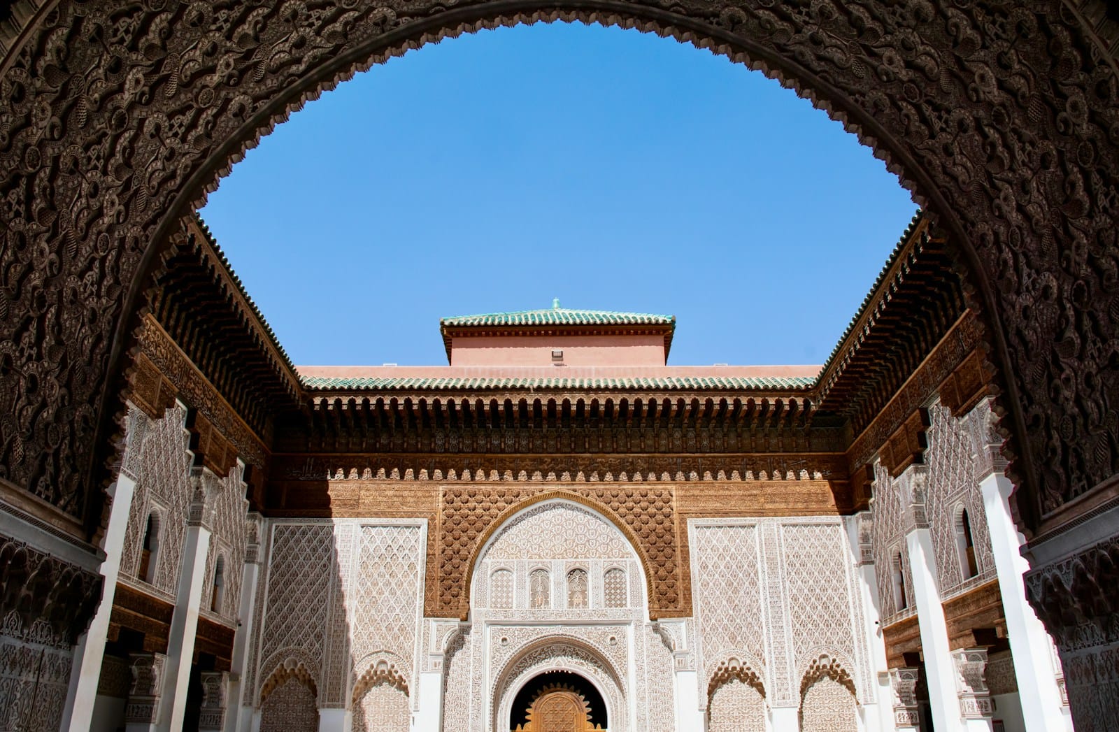 A building with arches and a clock tower in the background.Marrakech in February
