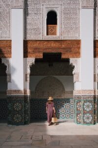a woman in a hat standing in front of a building.Morocco in July