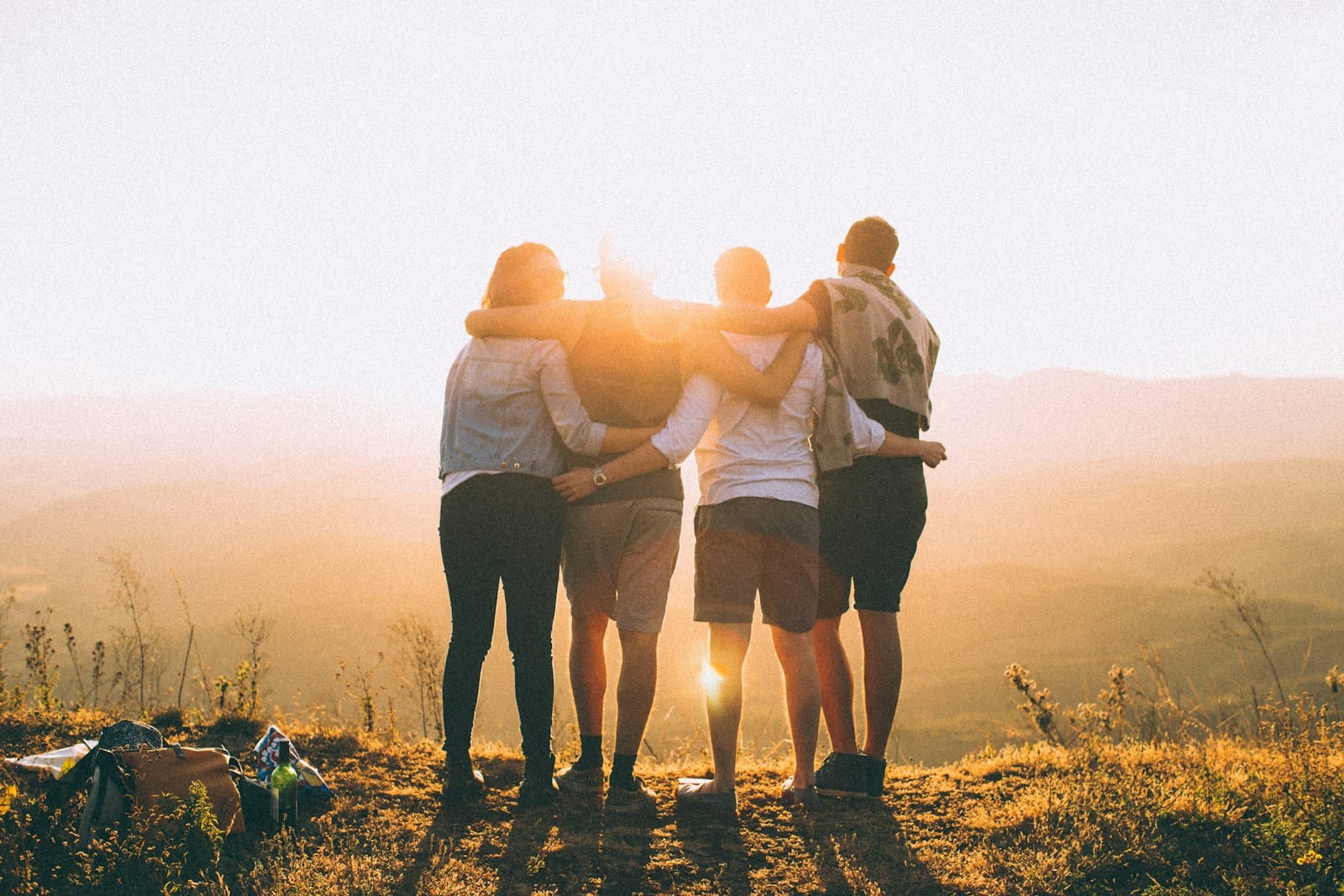 four person hands wrap around shoulders while looking at sunset,is morocco safe