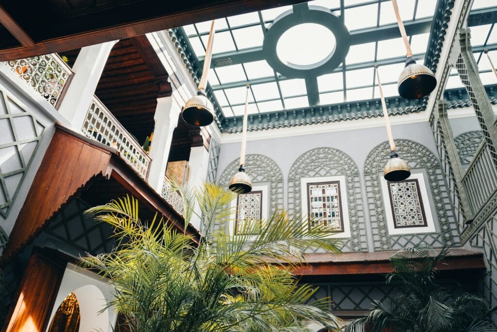 Interior courtyard with plants and hanging lamps.Hotels vs riads