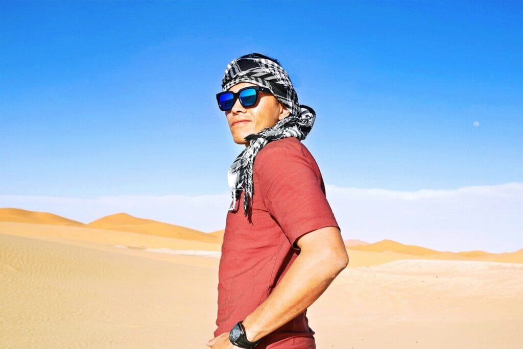 man in red t-shirt wearing black and white helmet standing on brown sand during daytime.What to Wear in Morocco as a Man