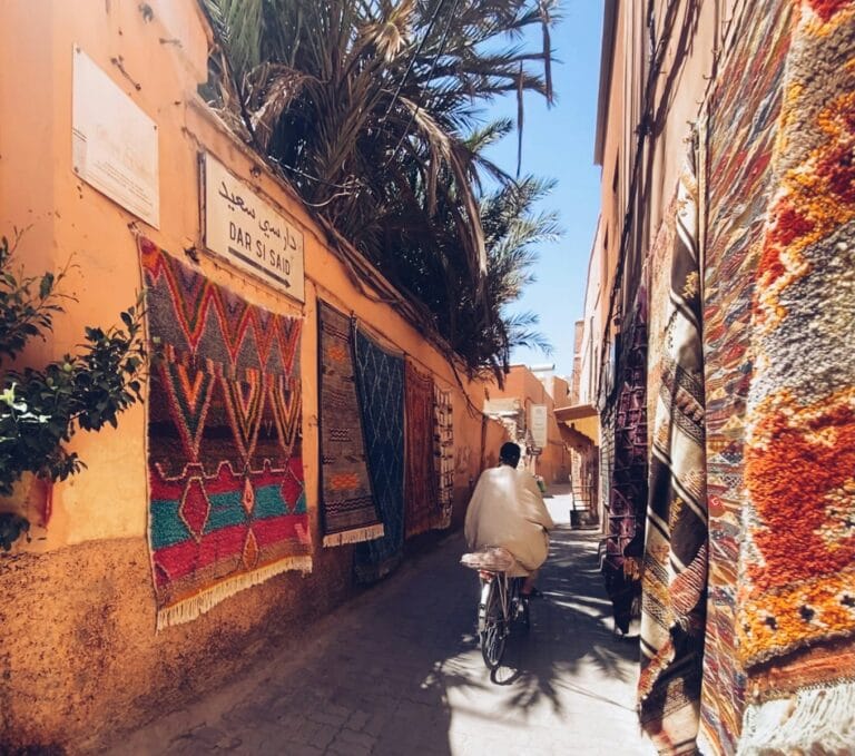 a man riding a bike down a narrow street.Hello in Moroccan