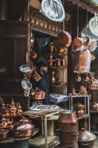 a man standing in front of a store filled with copper pots and pans.What to Do in Fes Morocco