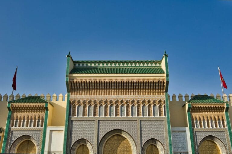 A large building with a lot of arches and flags on top of it.What to Do in Fes Morocco