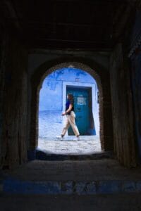 a woman walking through a tunnel with a blue door.Marokko Blauwestad