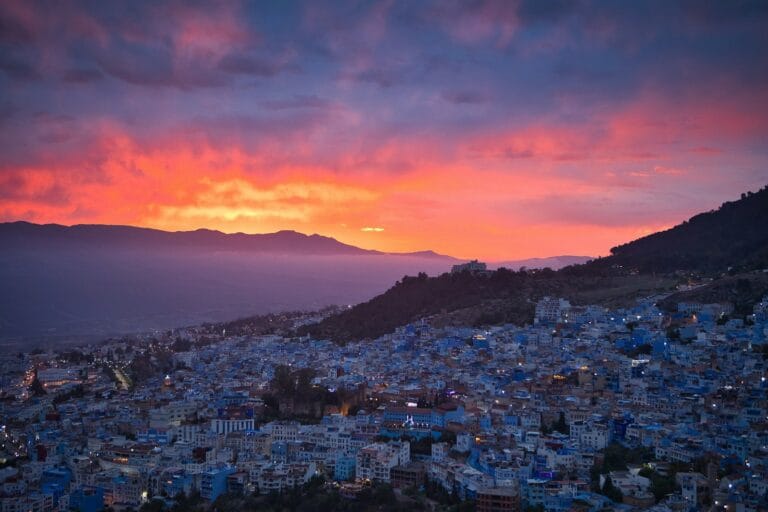 A sunset over a city with a mountain in the background.Marrakech to Chefchaouen