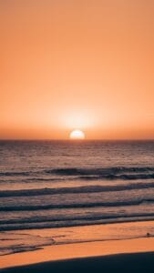 The sun is setting over the ocean on the beach.Agadir or Essaouira