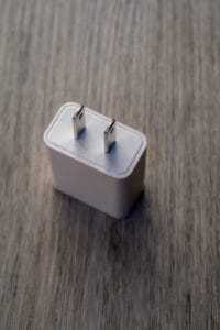 White power adapter with metal prongs on wood.plug