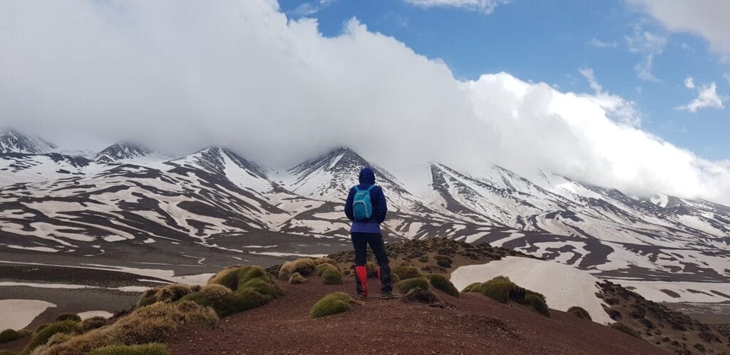 man standing on mountain with blue backpack during daytime.hiking in the atlas mountains
