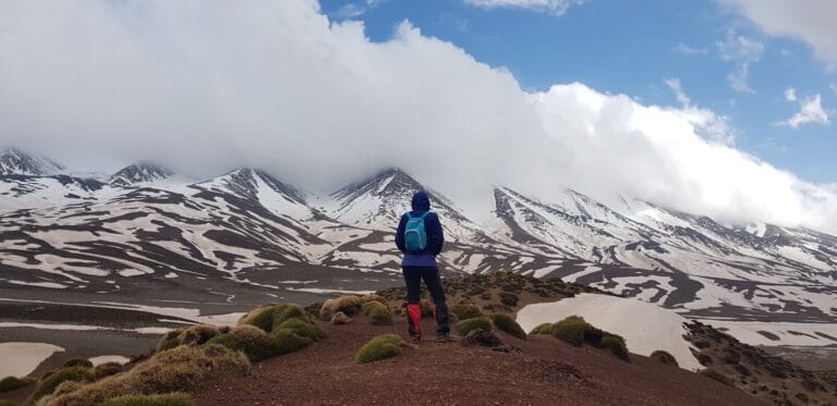 man standing on mountain with blue backpack during daytime.hiking in the atlas mountains