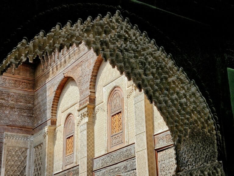 An arch in a building with a clock on it.Fes to Marrakech