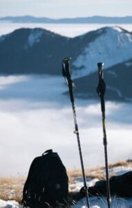 Two hiking poles and backpack with a stunning view of snow-covered mountains.