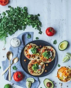 pizza with green leaves and red tomato on black ceramic plate.Morocco vegan