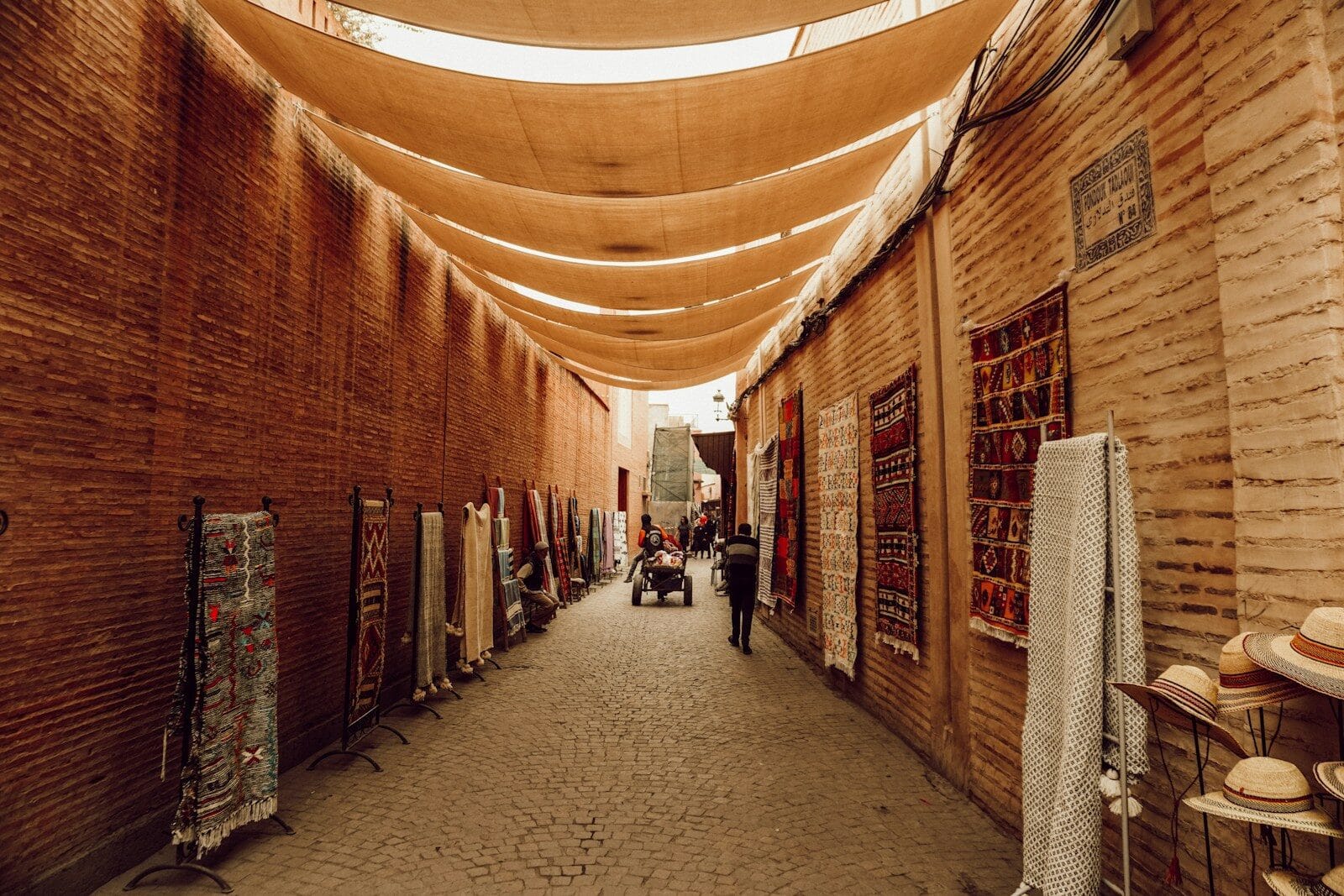 a narrow alley with a few people walking down it.what language is spoken in morocco