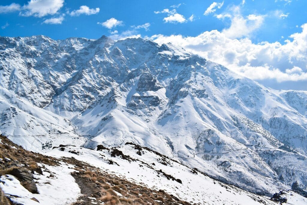 A mountain range covered in snow under a blue sky.map of Morocco atlas mountains