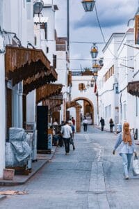 Scenic view of a Moroccan alley with traditional white buildings and street life. Ideal for travel and culture themes.
