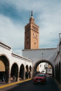 A sunny day view of Koutoubia Mosque minaret and surrounding arched market buildings in Marrakech, Morocco.