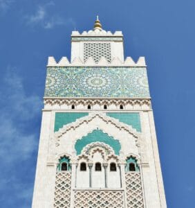 A striking vertical shot of the Hassan II Mosque's intricate minaret against a clear blue sky.weather for Morocco in March