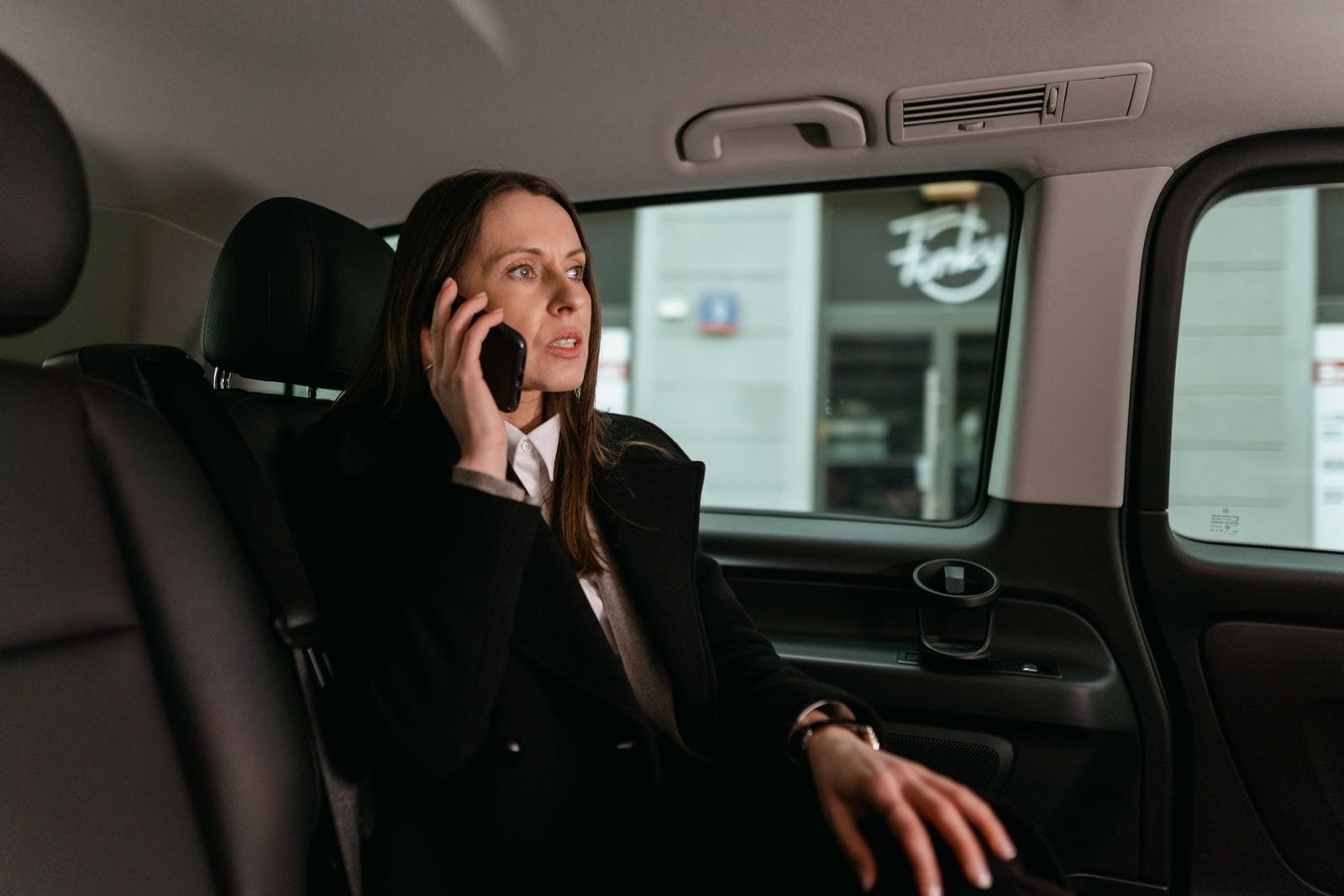 Confident businesswoman talking on phone inside a car. Professional attire, focused expression.uber in morocco
