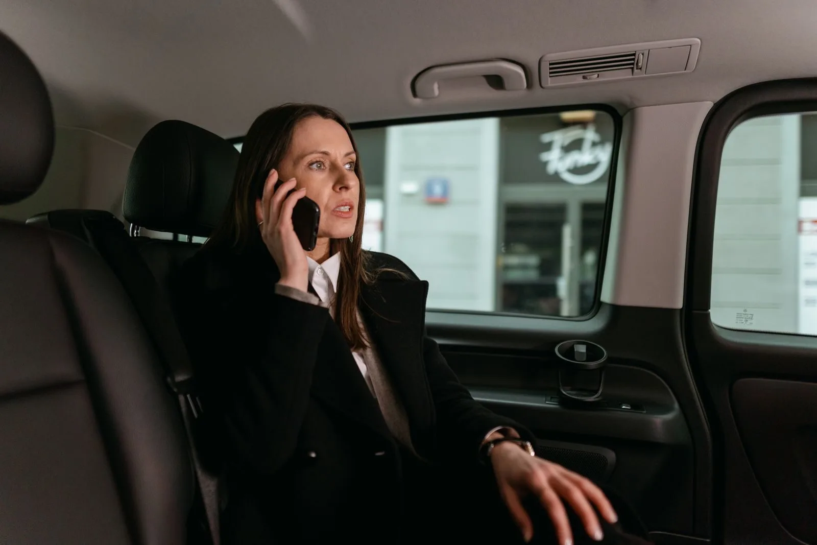 Confident businesswoman talking on phone inside a car. Professional attire, focused expression.uber in morocco