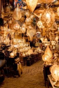 A vibrant display of traditional Moroccan hanging lamps in a Marrakech souk, glowing with golden light.Lanterns in Morocco