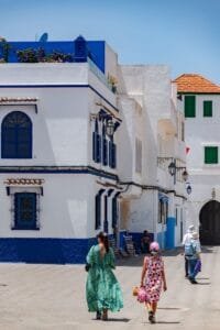 Tourists explore vibrant blue and white streets in a scenic urban setting.