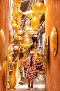Girl explores a vibrant Moroccan market filled with ornate golden lanterns and warm hues.Lanterns in Morocco