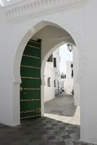 Explore the stunning architecture of Asilah, Morocco with this image of a traditional green archway.Is Asilah Worth Visiting for Families