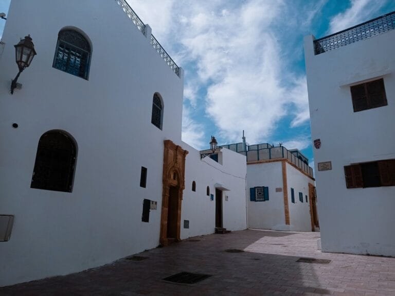 Picturesque alley featuring traditional whitewashed Mediterranean architecture under a bright blue sky.What to do in Asilah with kids?