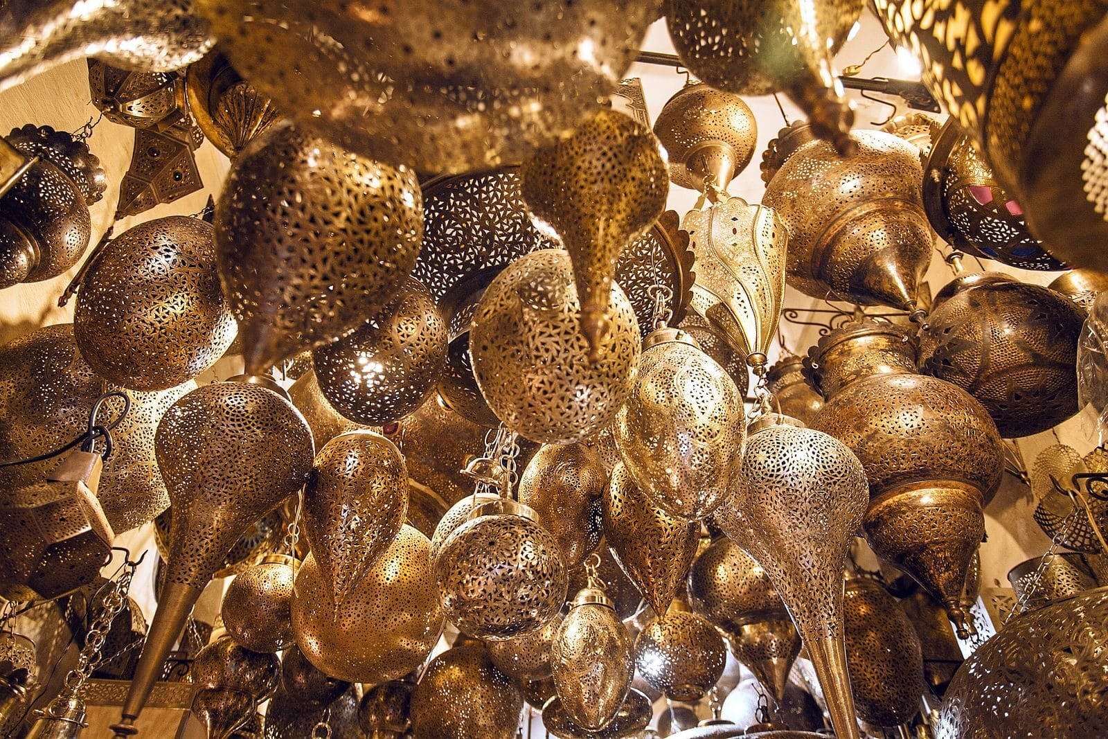 From below of assorted ornamental Moroccan lamps with tiny holes on shiny surface in local market.Lanterns in Morocco
